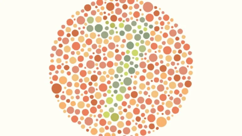 A picture of an Ishiara test. Dots in shades of red and green arranged in a circle, with a 7 visible to non-colorblind viewers.