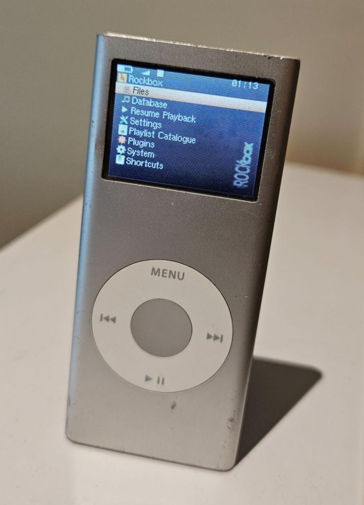 An image showing the Rockbox user interface running on a silver iPod nano.